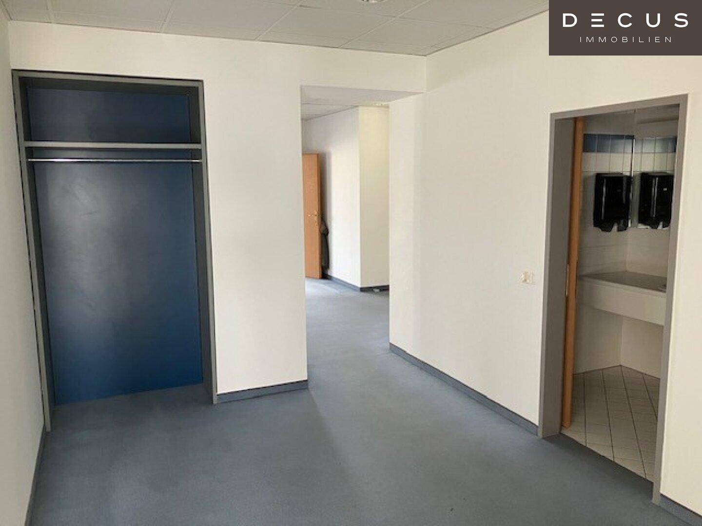 Flur mit Zugang zu einem Abstellraum und einem Waschraum, ausgestattet mit Vinylboden.