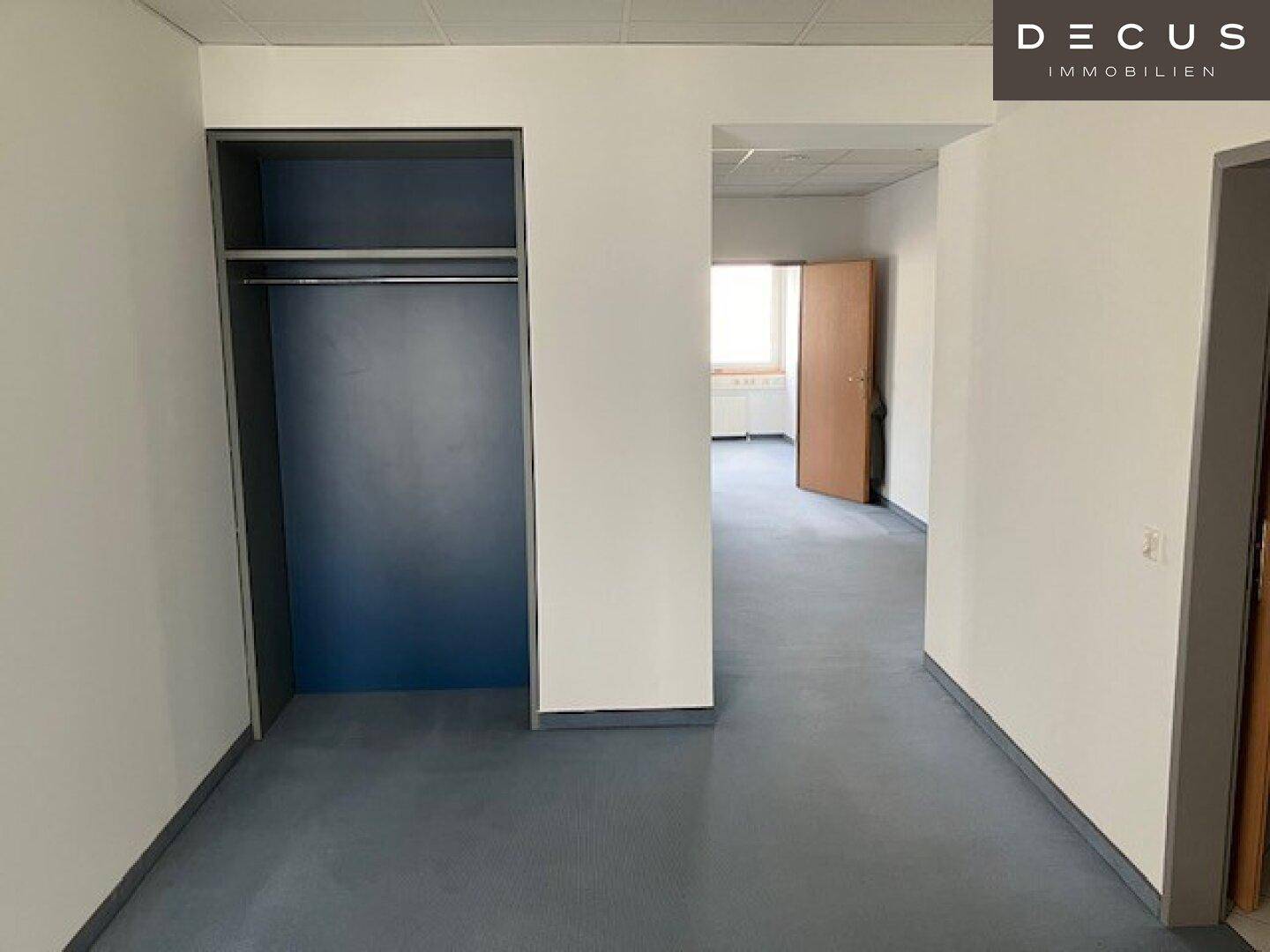 Heller Flur mit integriertem Schrankbereich und Blick in einen weiteren Raum mit Tür.