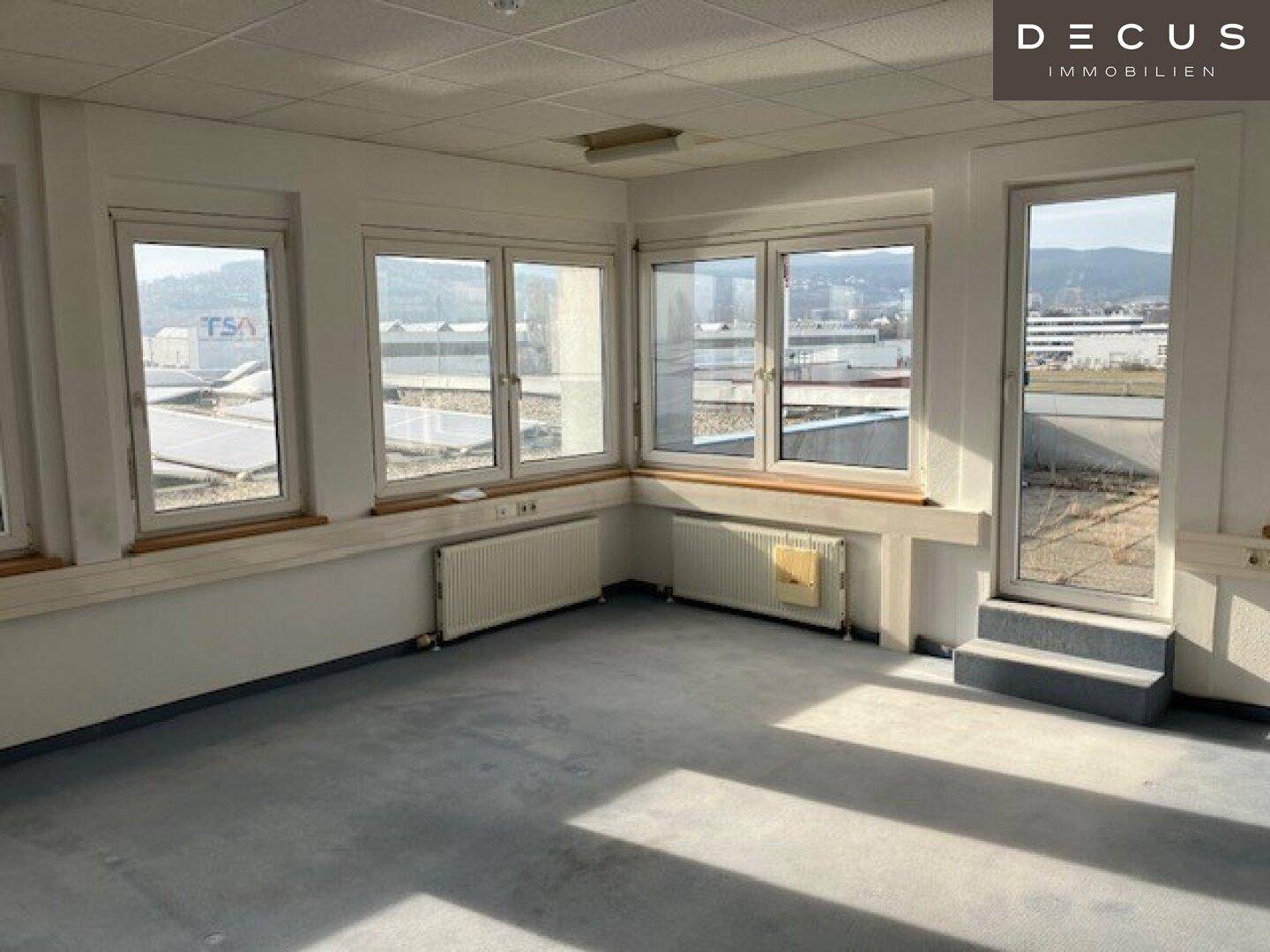 Heller Büroraum mit großen Fenstern und Blick auf die Umgebung, ausgestattet mit Heizkörpern.