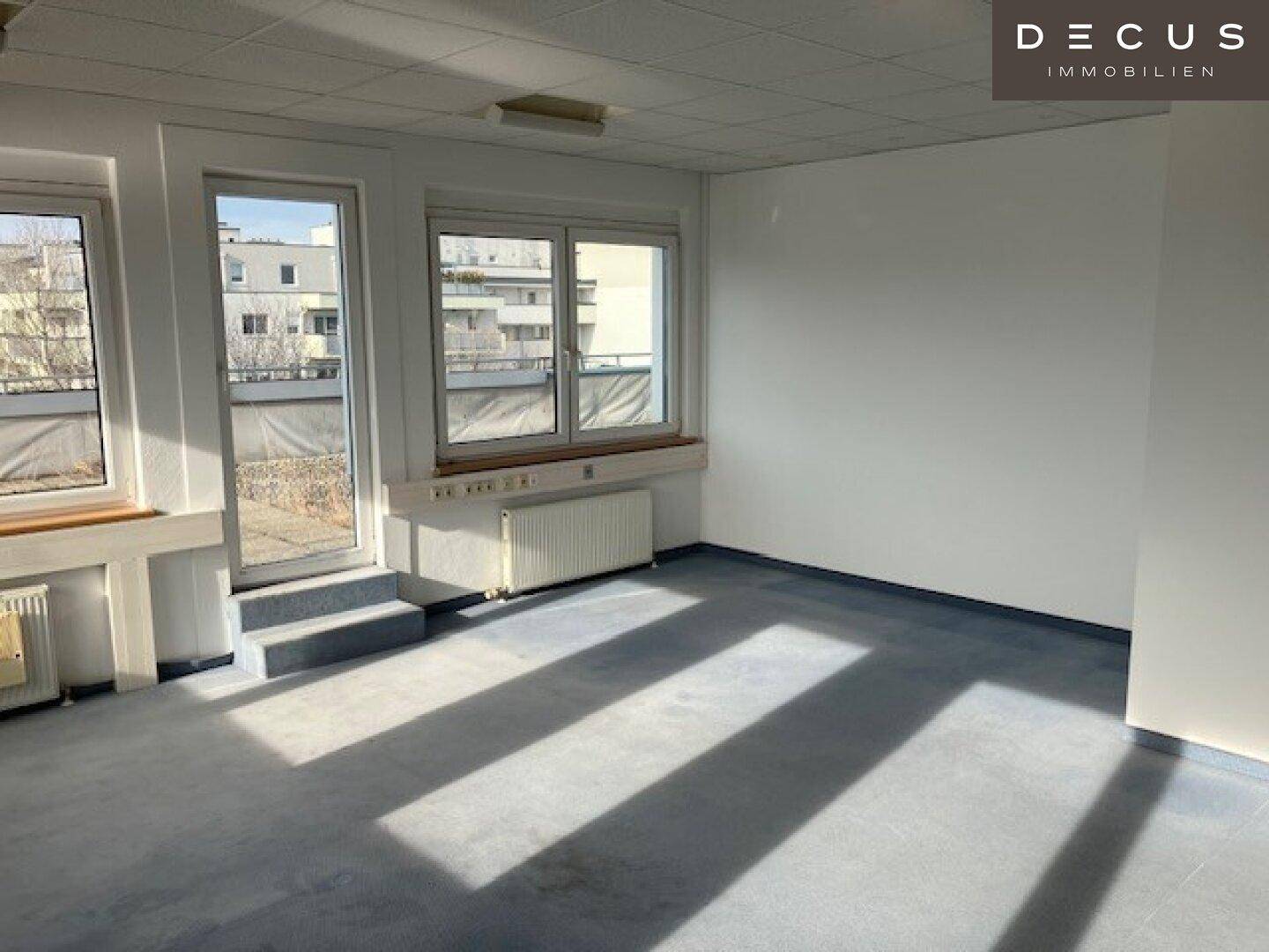 Heller Büroraum mit großen Fenstern und Zugang zu einem Außenbereich, ideal für Arbeitsplätze.