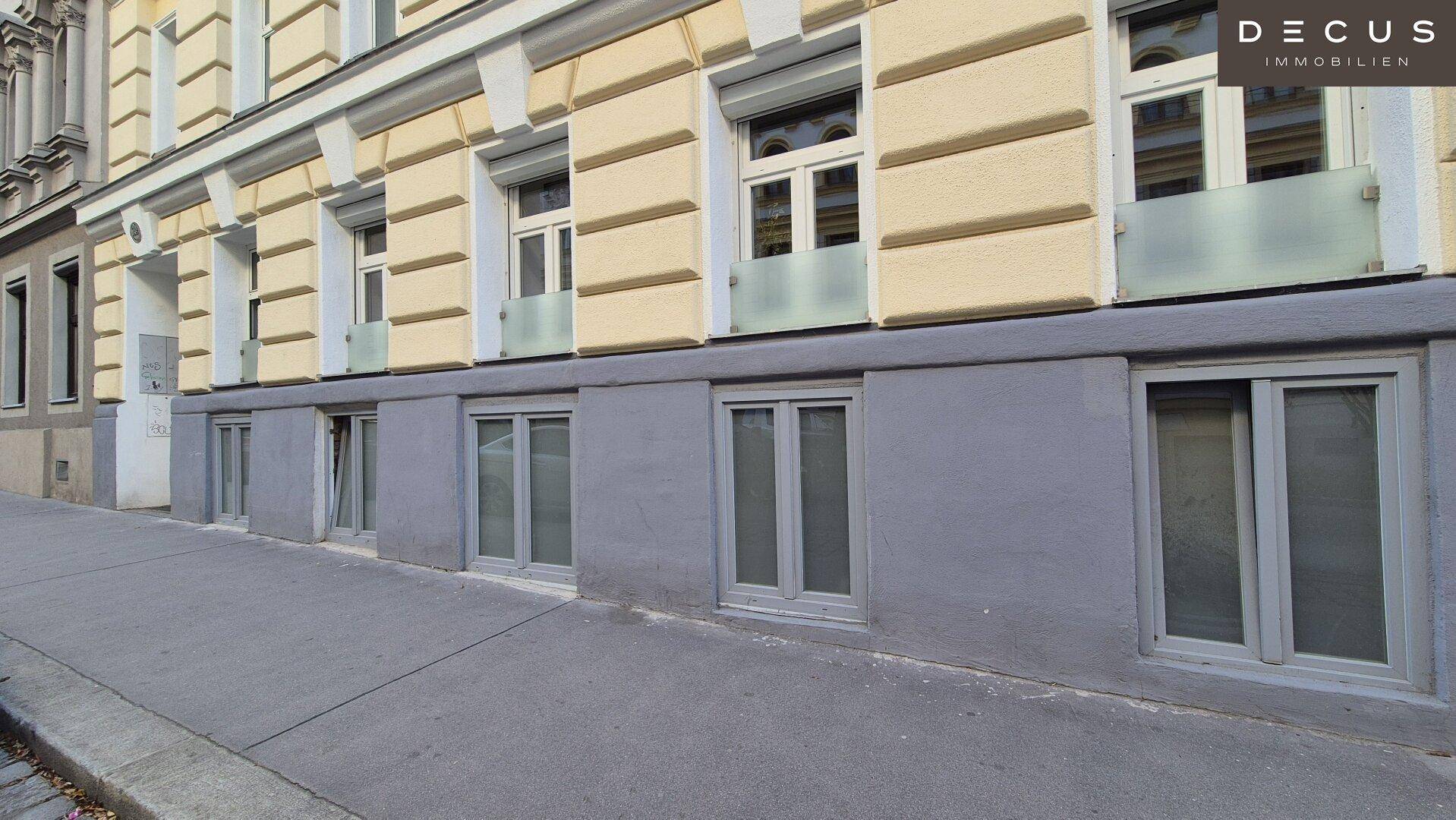 Erdgeschossfassade eines Gebäudes mit großen Fenstern und Zugang zur Straße.