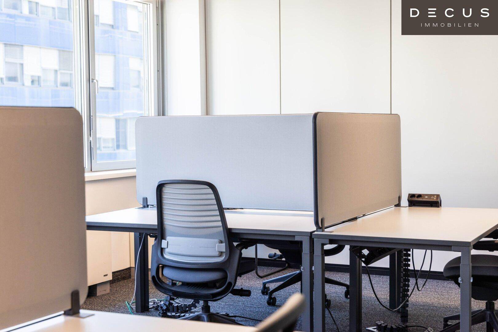 Detailansicht eines modernen Büroschreibtisches mit ergonomischem Stuhl und Sichtschutz.