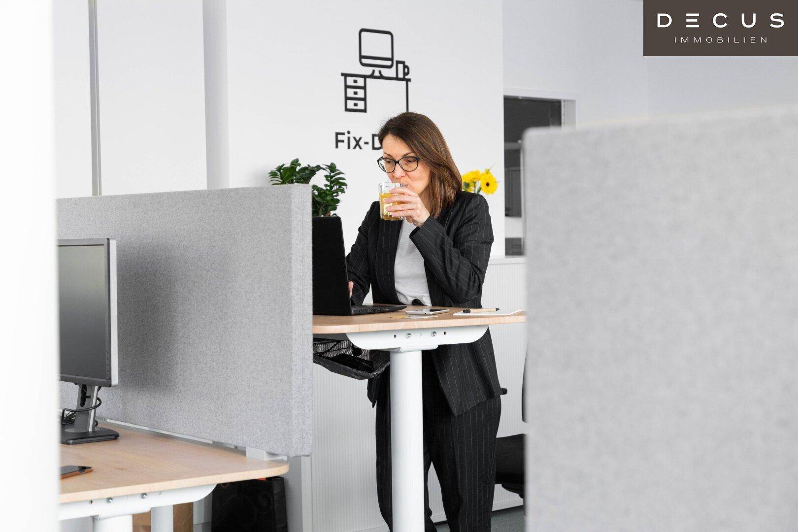 Eine Person arbeitet an einem höhenverstellbaren Schreibtisch in einem modernen und hellen Büroambiente.