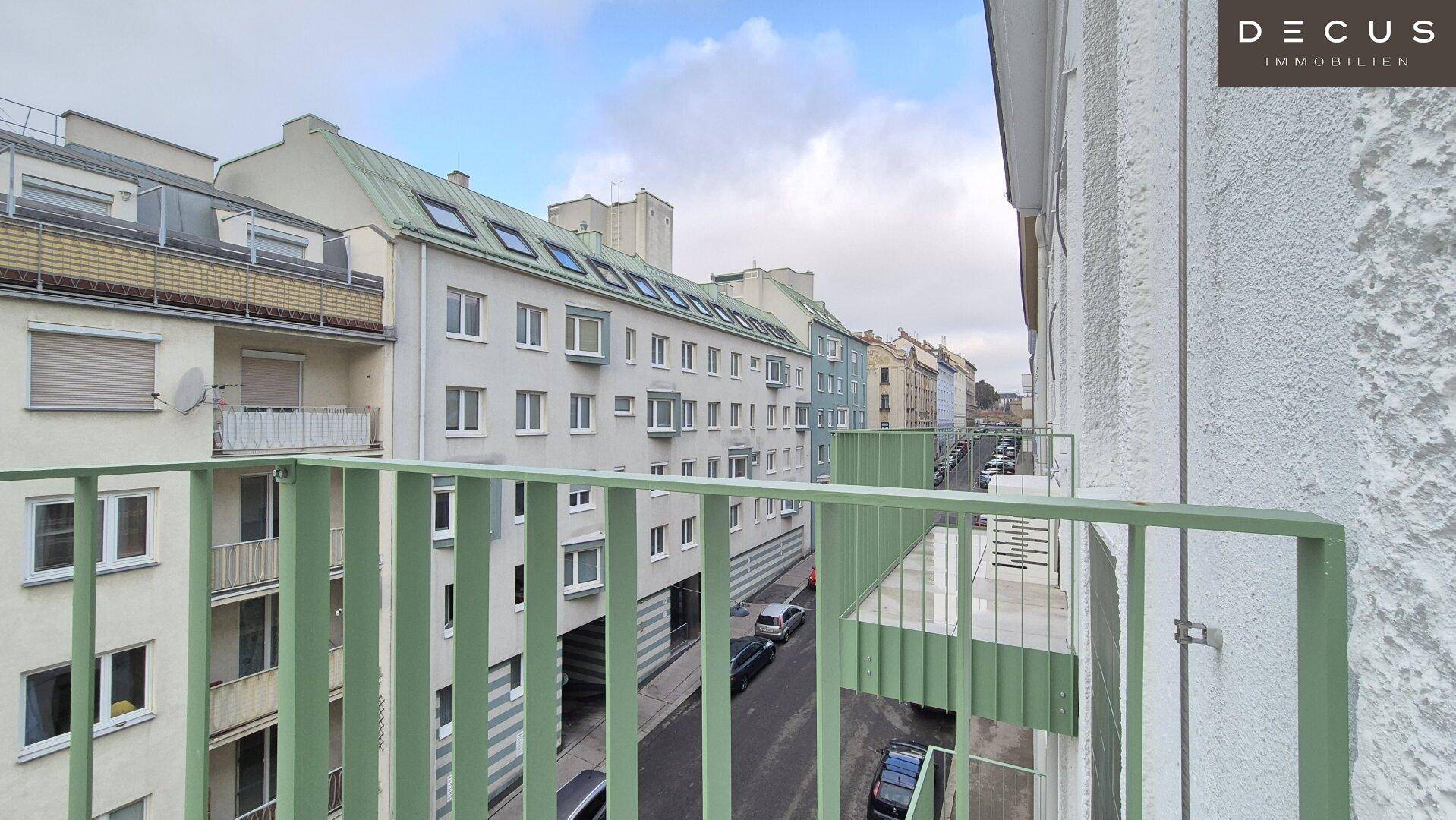 Blick von einem Balkon auf die umliegende Straße und weitere Gebäude.
