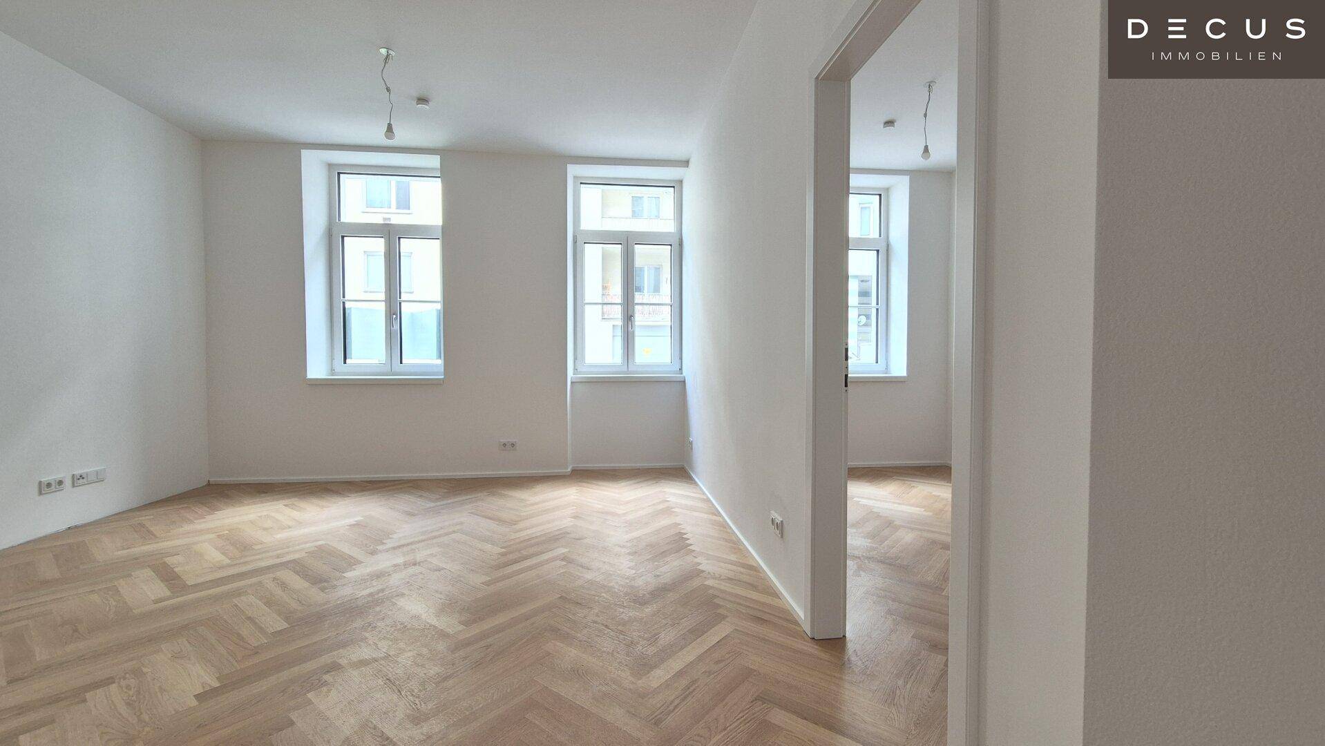 Heller Wohnraum mit Fischgrätparkettboden und großen Fenstern, bereit zur individuellen Gestaltung.
