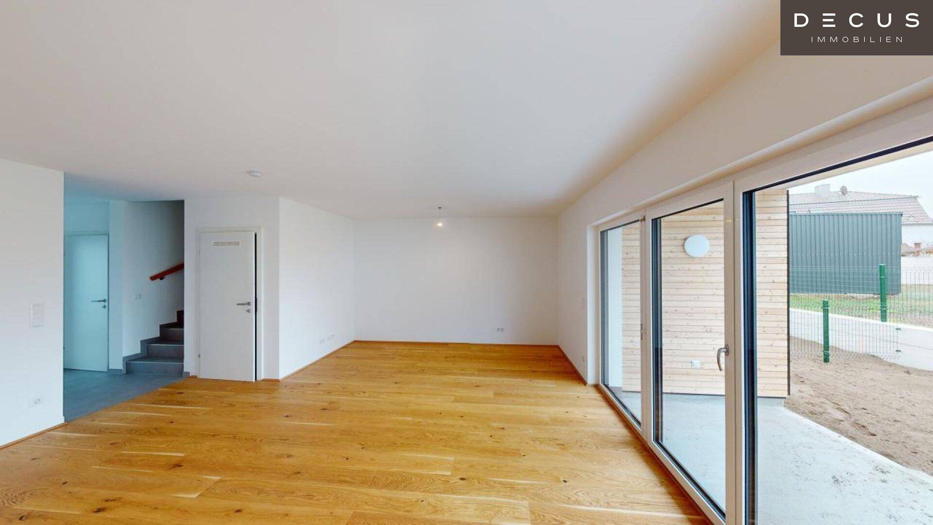 Geräumiger Wohnbereich mit Holzboden und Zugang zur Terrasse oder zum Garten.