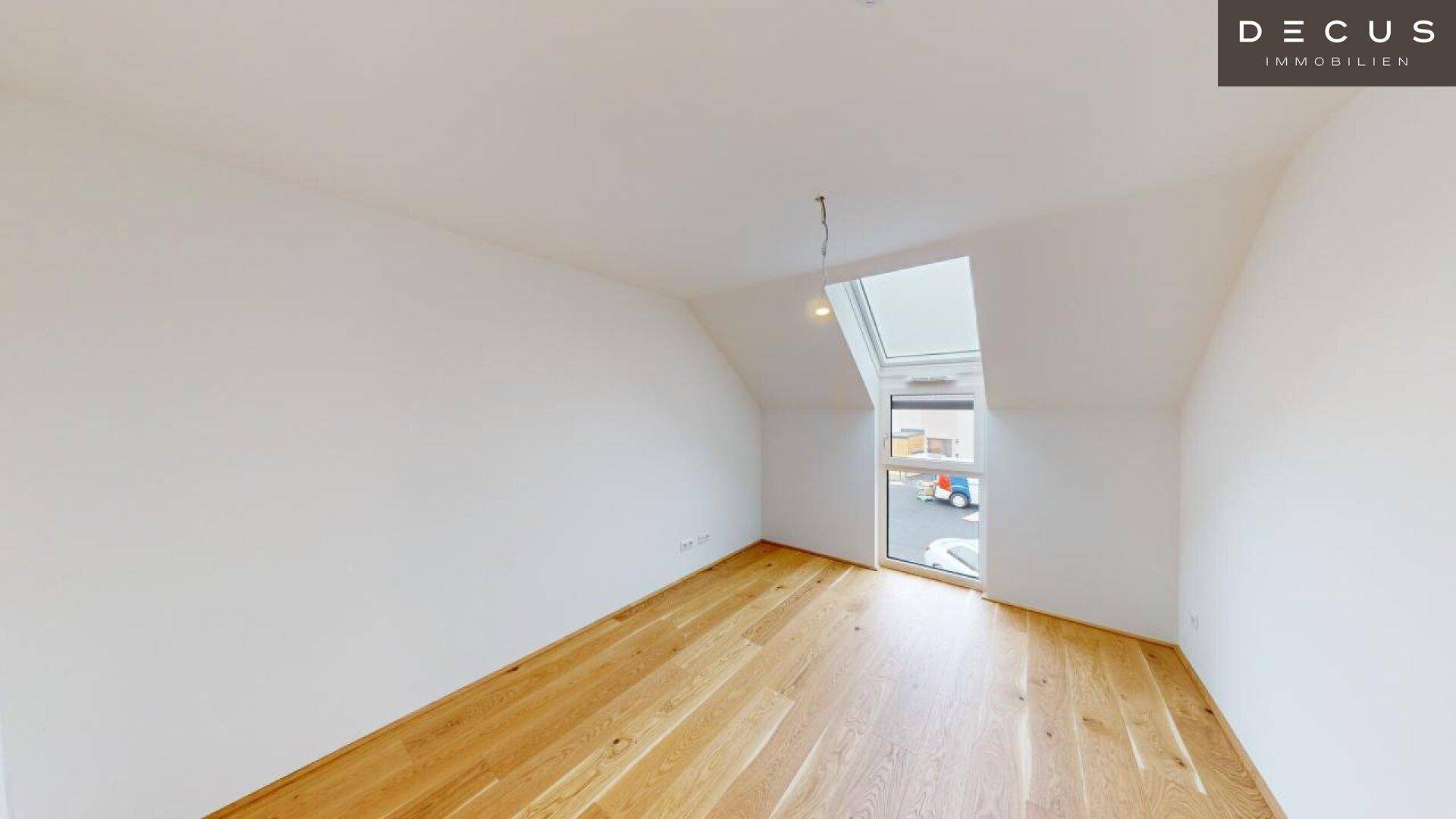 Schlafzimmer im Dachgeschoss mit Holzboden und großem Dachfenster für viel Tageslicht.