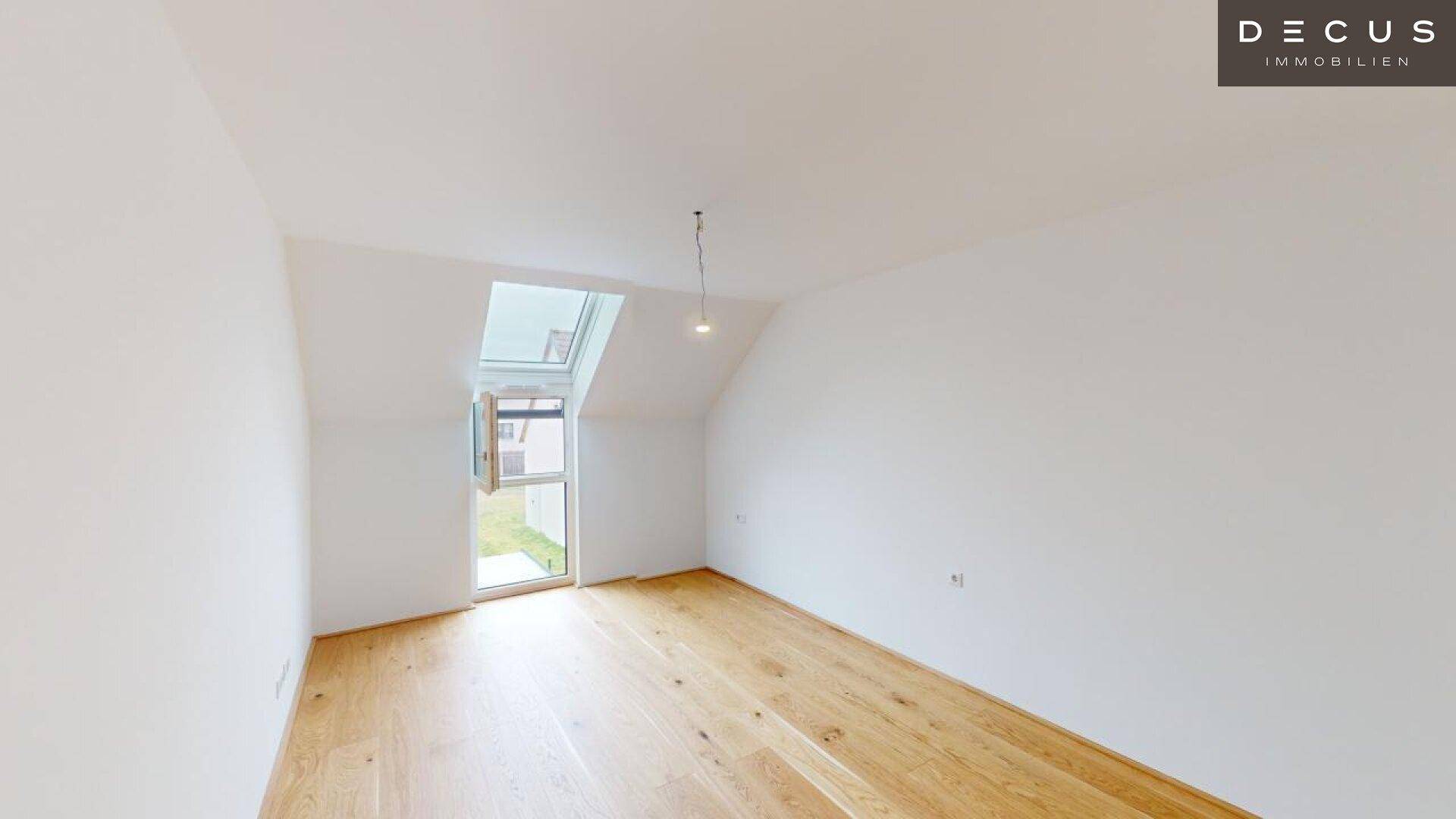 Helles Schlafzimmer im Dachgeschoss mit Holzboden und schrägem Dachfenster.