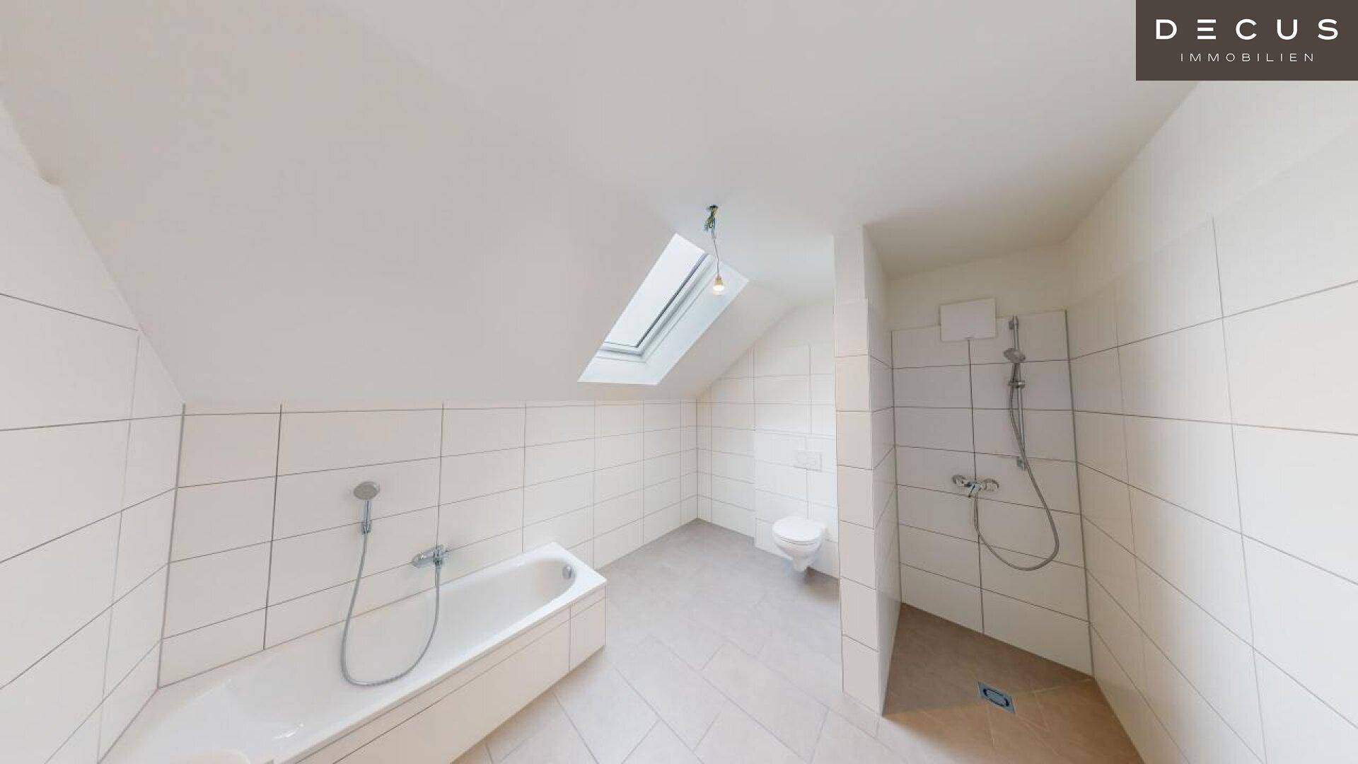 Modernes Badezimmer im Dachgeschoss mit Badewanne, Dusche und Dachfenster.
