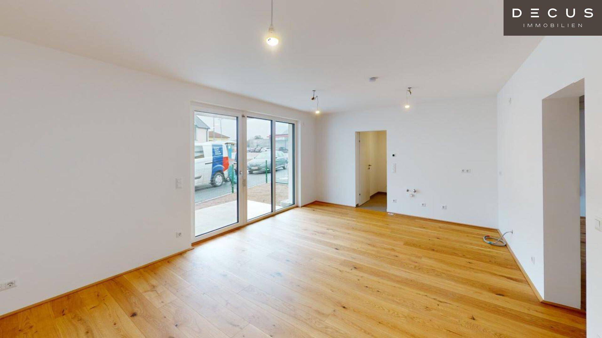 Geräumiges Zimmer mit Holzboden und großen Glasschiebetüren für viel Helligkeit.