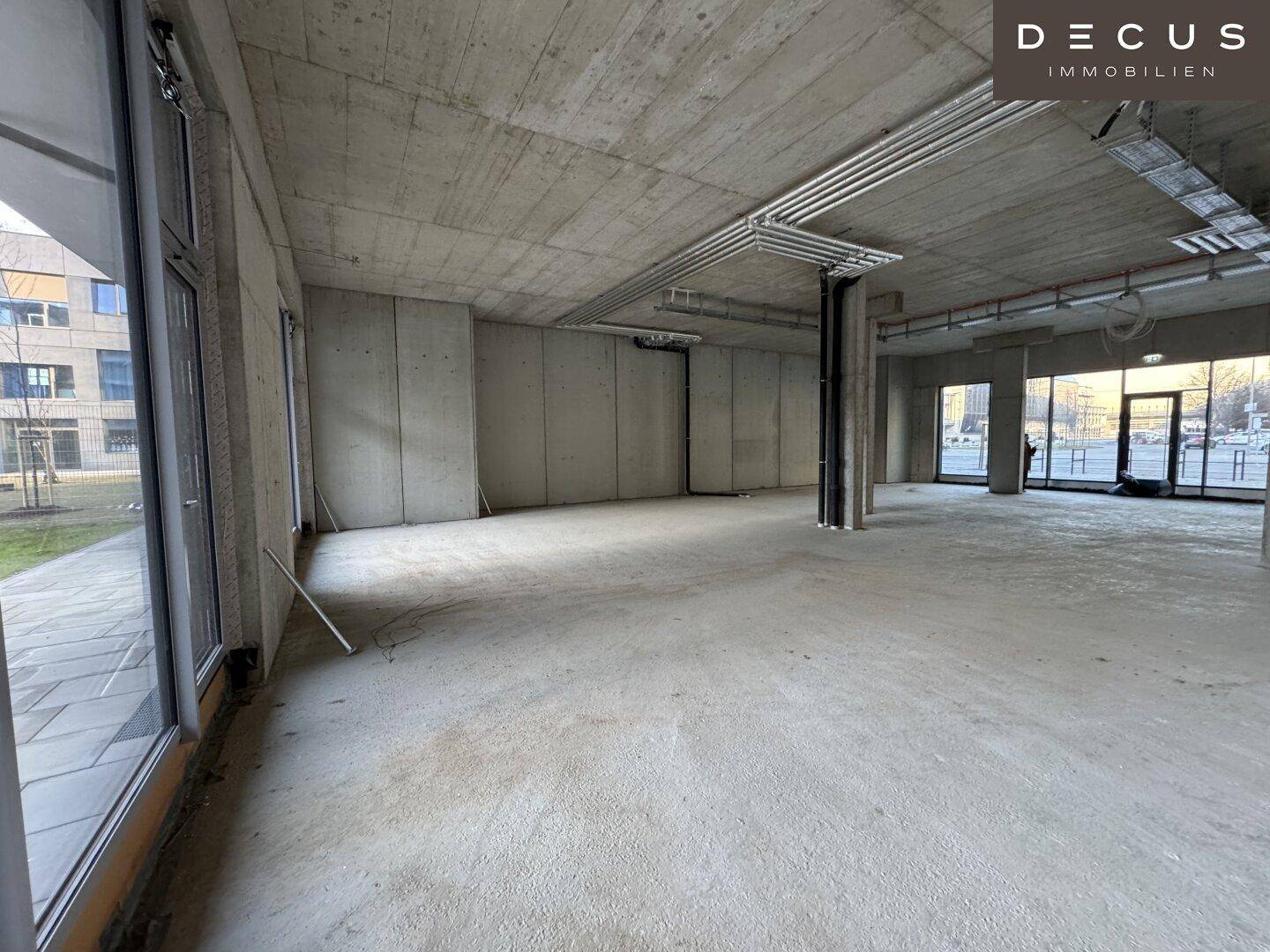 Heller Gewerberaum mit großen Fenstern, die einen Blick auf die umliegende Grünfläche bieten.