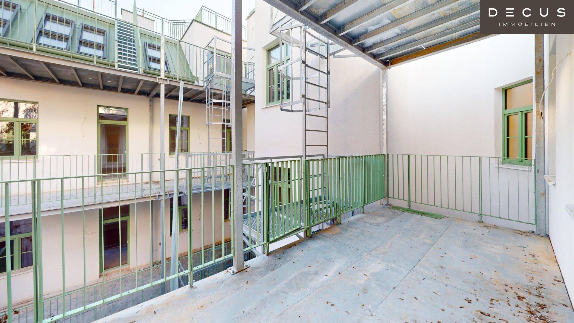 Geräumiger Balkon mit Metallgeländer und Blick auf den Innenhof des Gebäudes.
