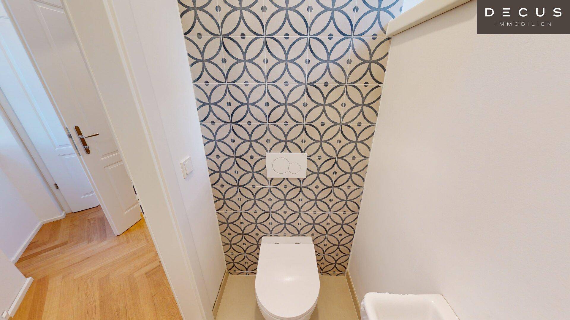 Stilvolles Gäste-WC mit modernem Wand-WC und dekorativen Fliesen an der Wand.