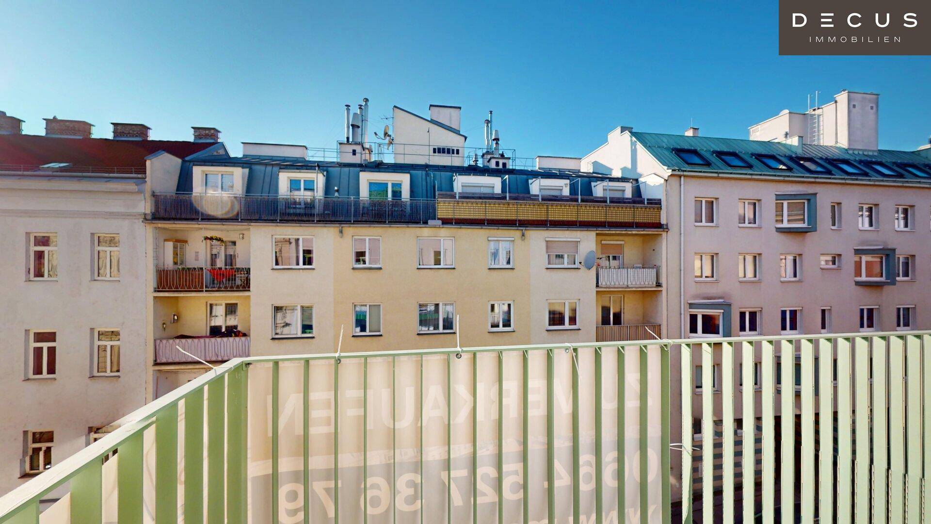 Blick auf gegenüberliegende Wohngebäude mit verschiedenen Fassaden und Balkonen unter blauem Himmel.