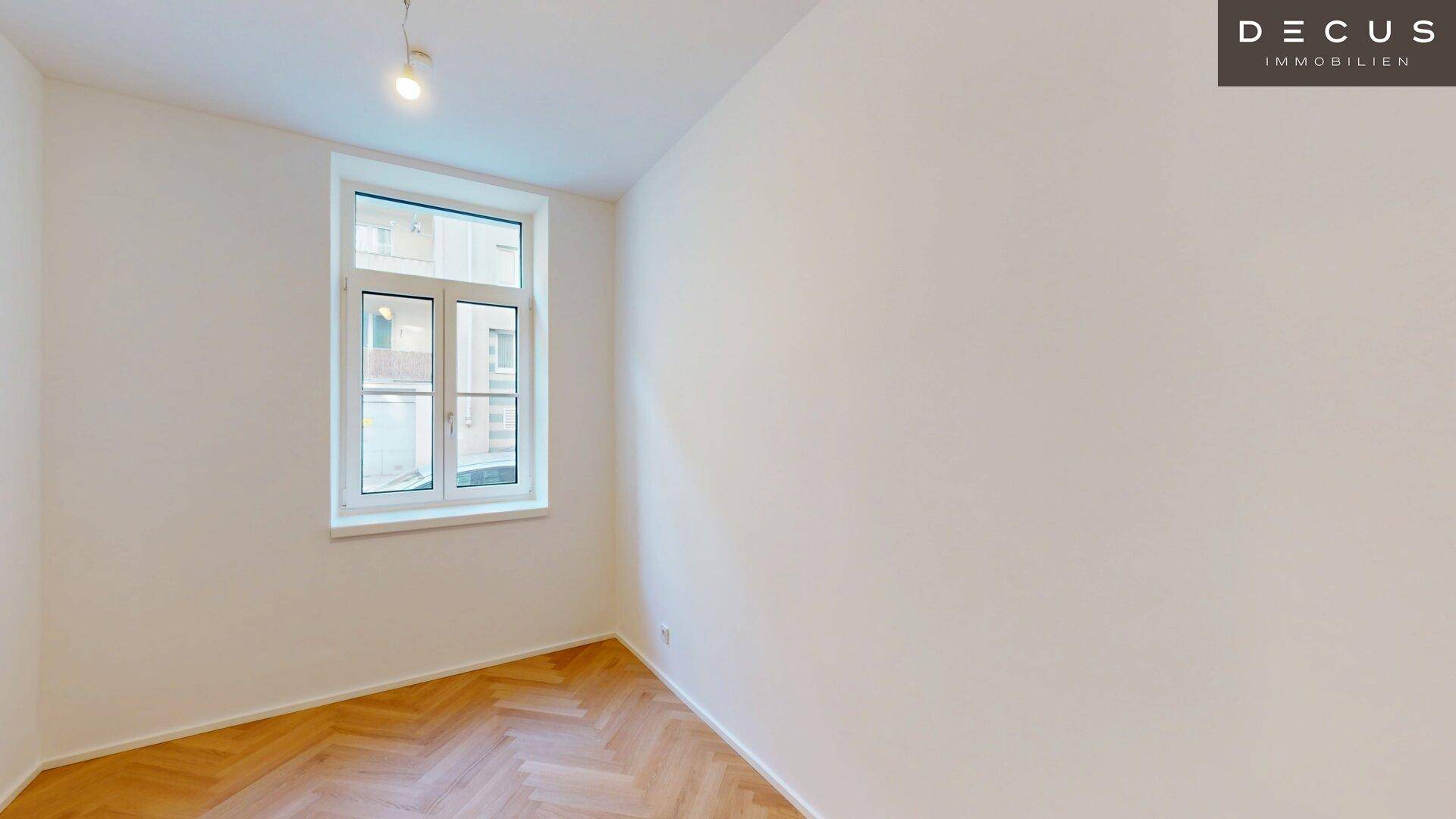 Gemütliches Zimmer mit Fischgrätparkett und einem großen Fenster für viel Tageslicht.