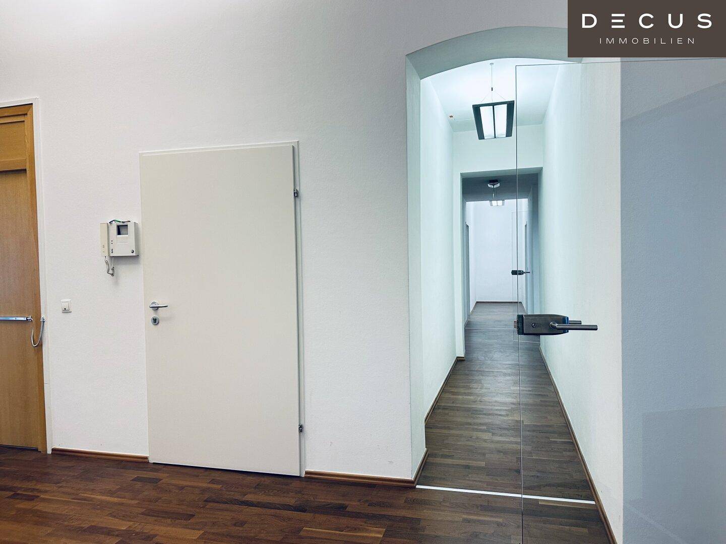 Langer Flur mit Holzboden und einer eleganten Bogenöffnung, der zu weiteren Räumen führt und eine klassische Note verleiht.