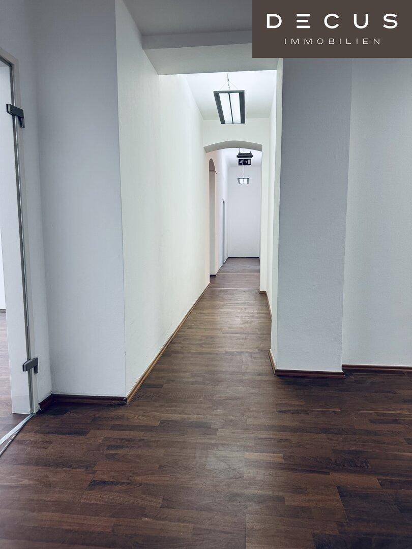 Heller Flur mit Holzboden und weiß gestrichenen Wänden, der eine klare und funktionale Verbindung zwischen den Räumen bietet.