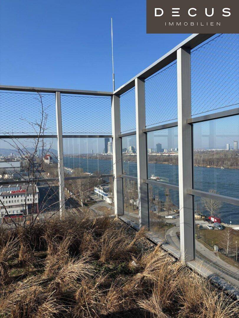 Aussichtsterrasse mit weitem Blick über die Stadt und den Fluss unter klarem Himmel.