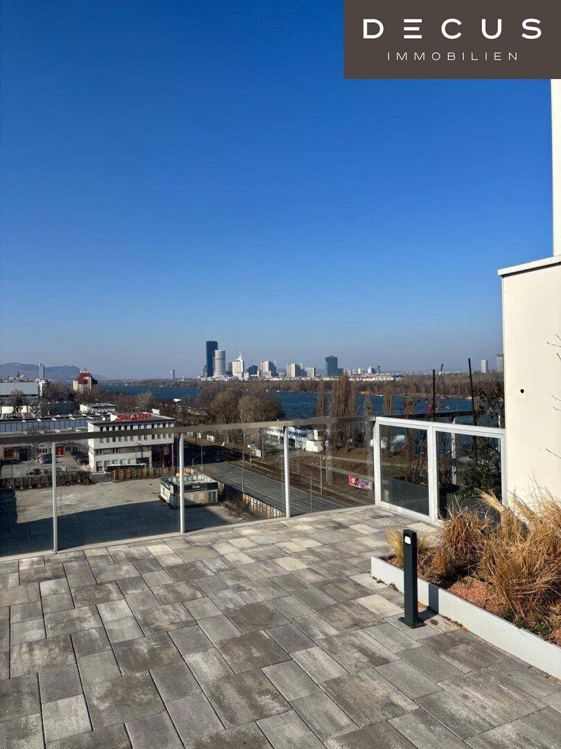 Großzügige Dachterrasse mit moderner Pflasterung und weitem Blick auf die Stadt und das Wasser.