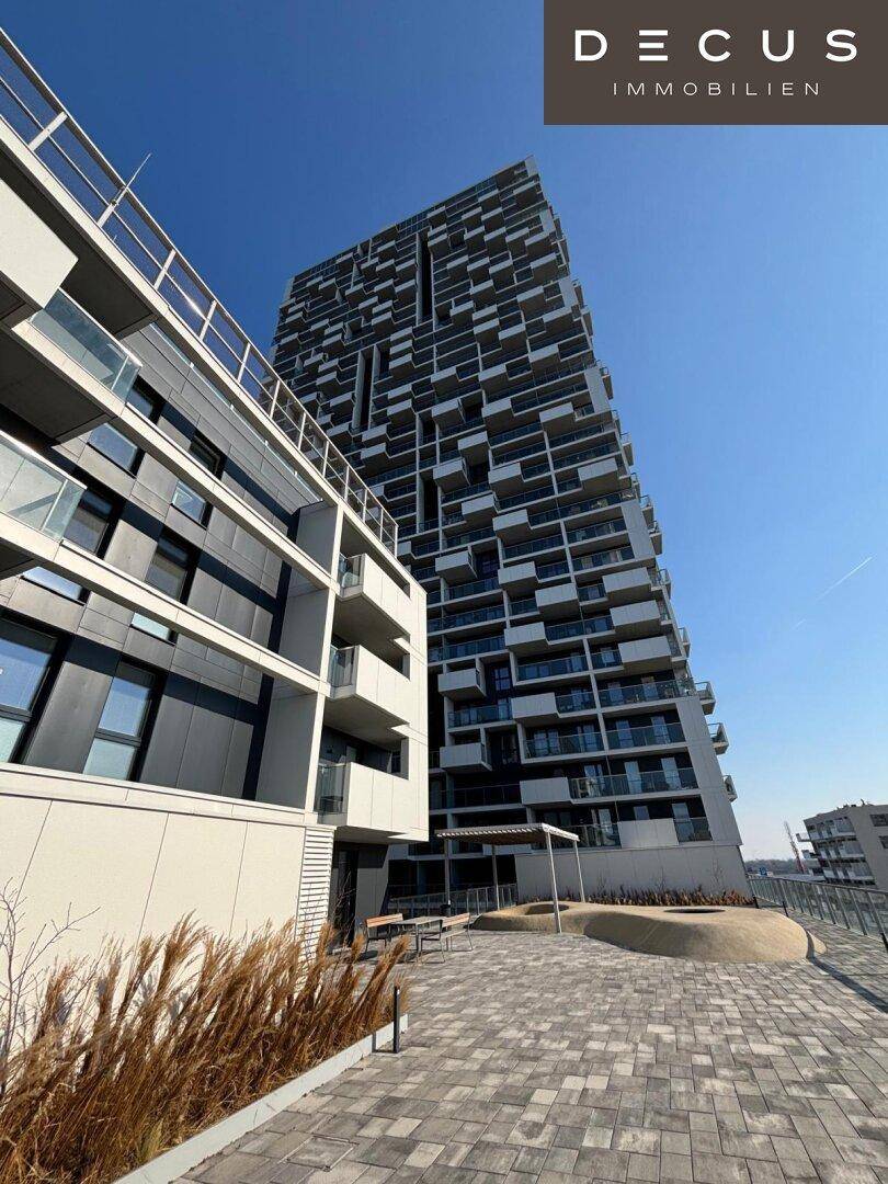 Beeindruckendes modernes Hochhaus mit markanter Fassade und vielen Balkonen unter blauem Himmel.