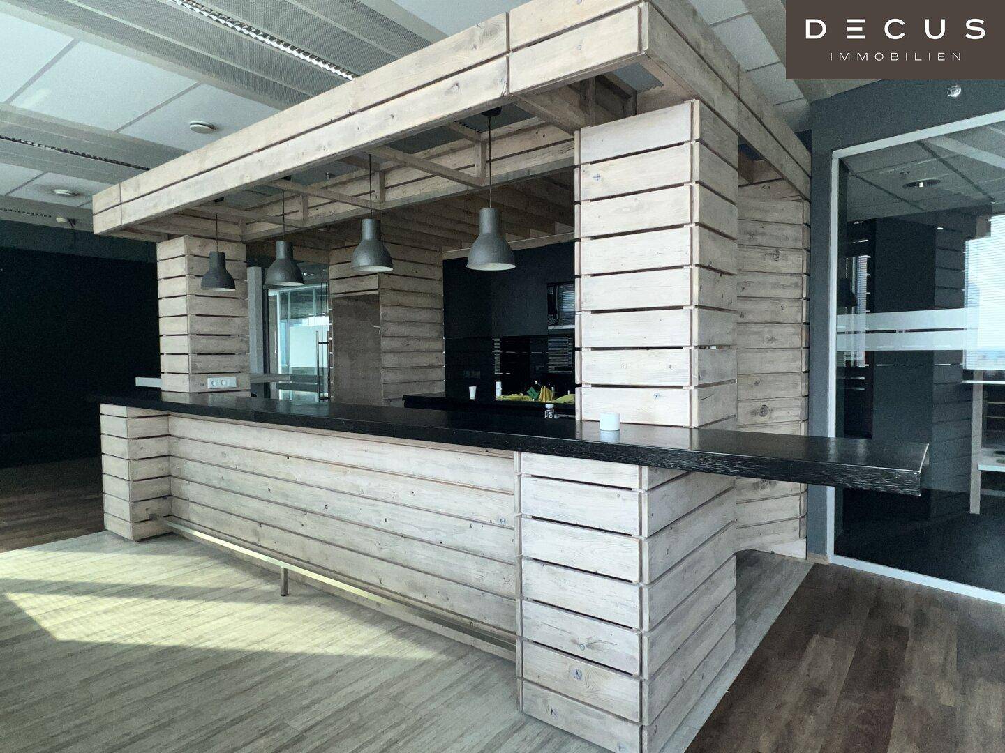 Rustikale Bar aus hellem Holz mit dunkler Arbeitsplatte und modernen Pendelleuchten.