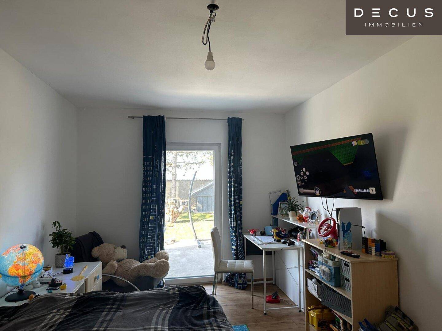 Helles Kinderzimmer mit Zugang zur Terrasse und Blick in den Garten.