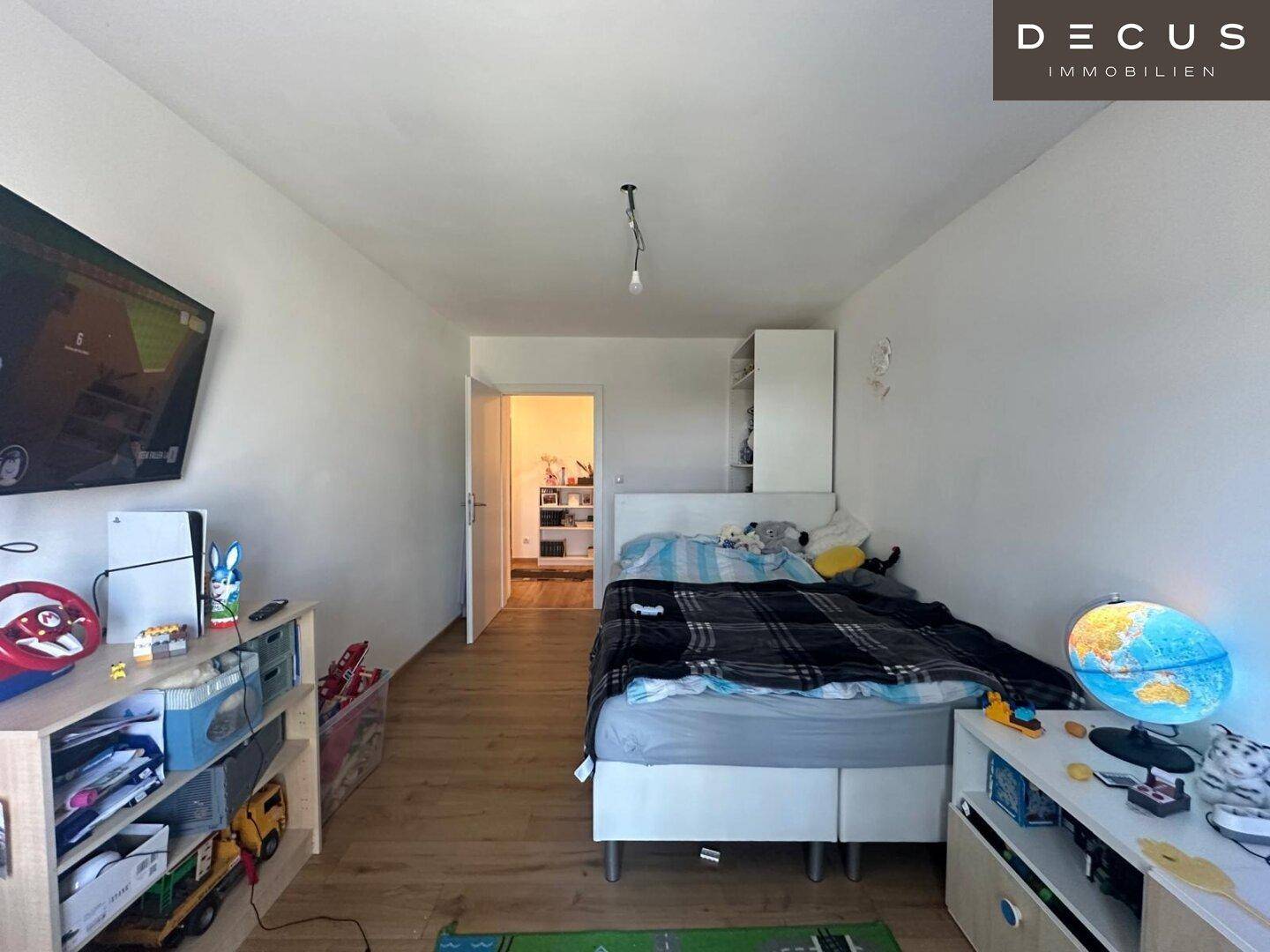Kinderzimmer mit Bett, Spielzeug und Blick auf den Flur.