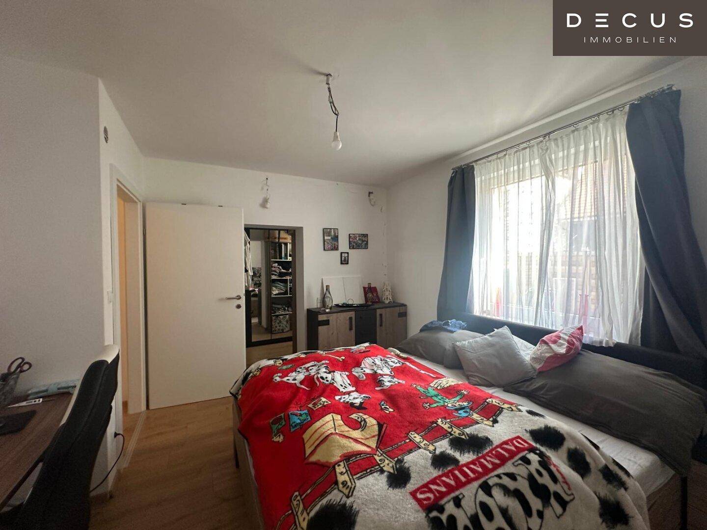 Schlafzimmer mit Holzboden und Zugang zu einem begehbaren Kleiderschrank.