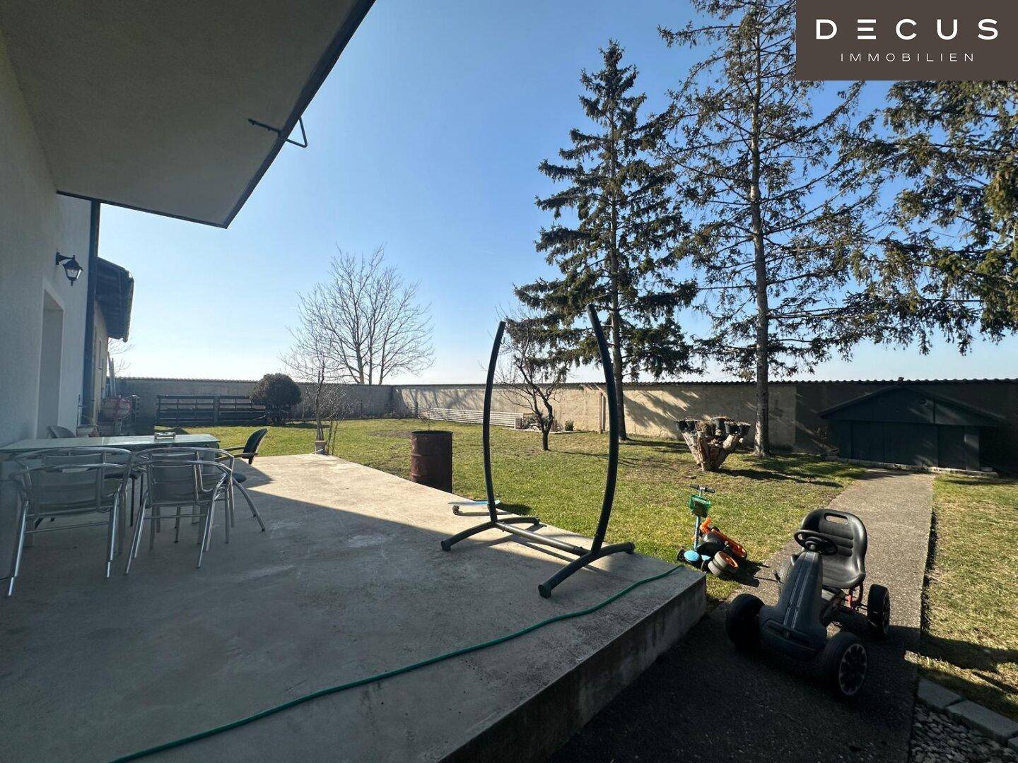 Große Terrasse mit Gartenmöbeln und weitem Blick ins Grüne.