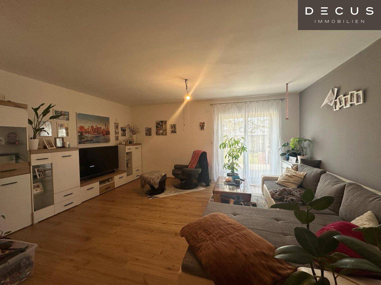 Helles Wohnzimmer mit großem Sofa, TV-Möbeln und Zugang zum Außenbereich.