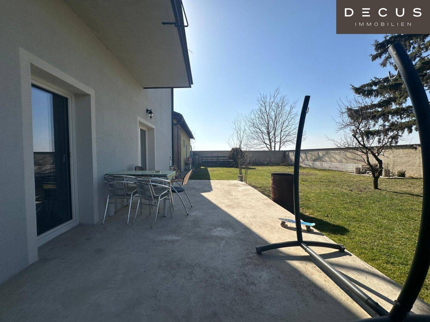 Sonniger Terrassenbereich mit Gartenmöbeln und direktem Zugang zum Garten.