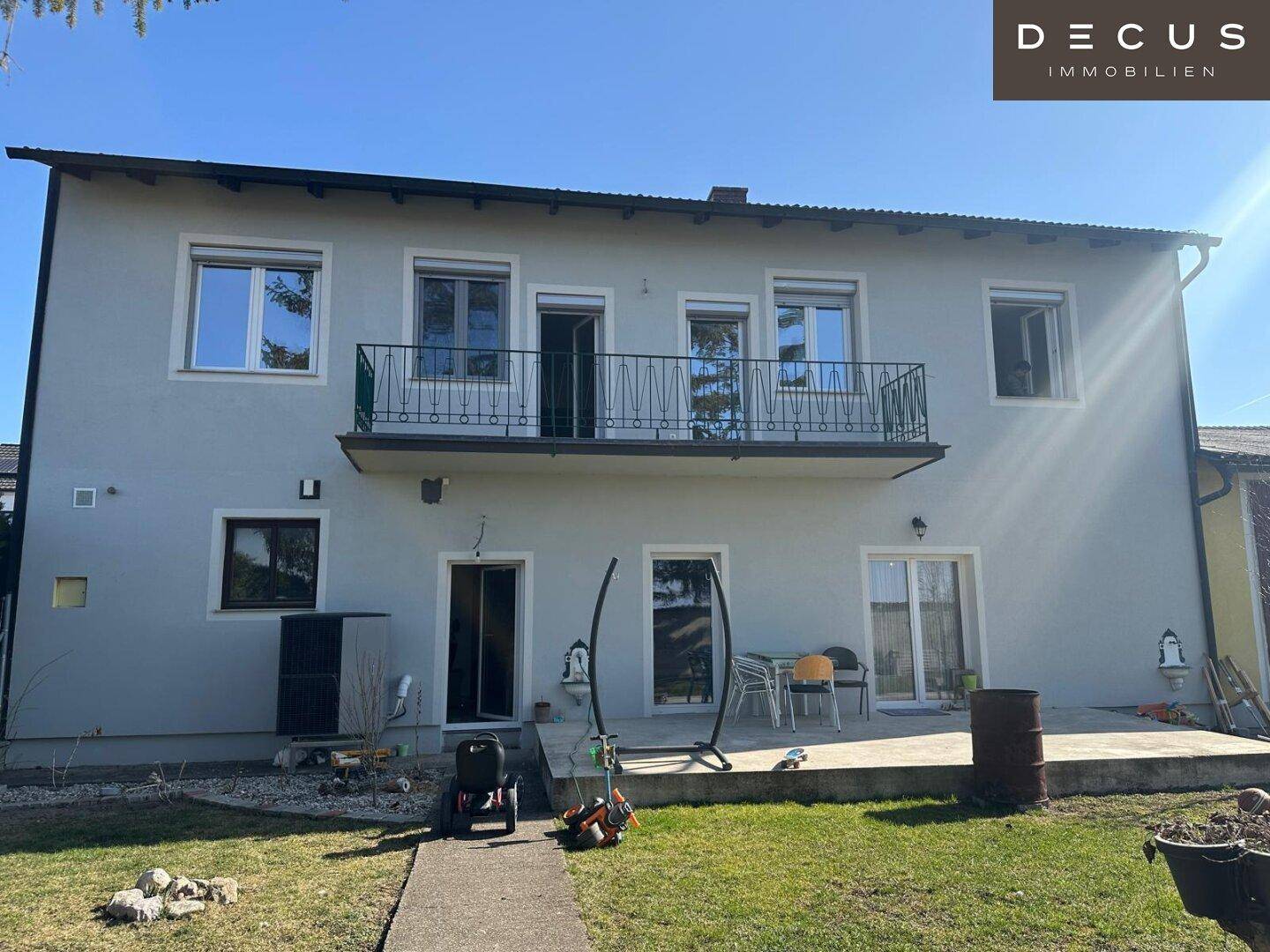Rückseite des Hauses mit Balkon, Terrasse und weitläufigem Garten.