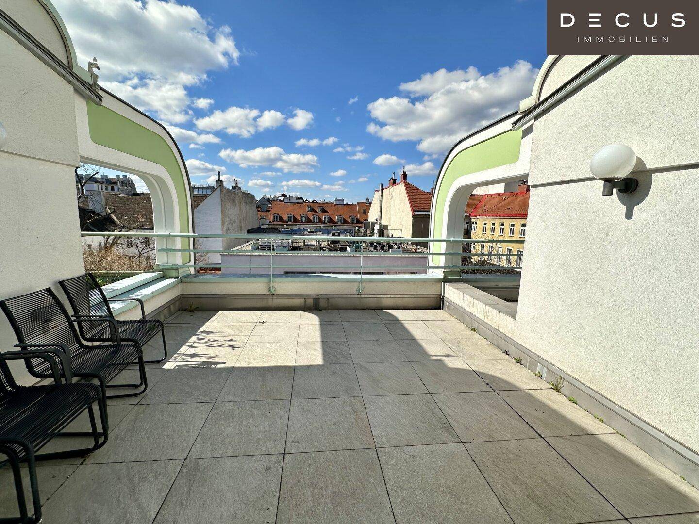 Geräumige Dachterrasse mit Sitzgelegenheiten und weitem Blick über die Stadt und die Dächer.