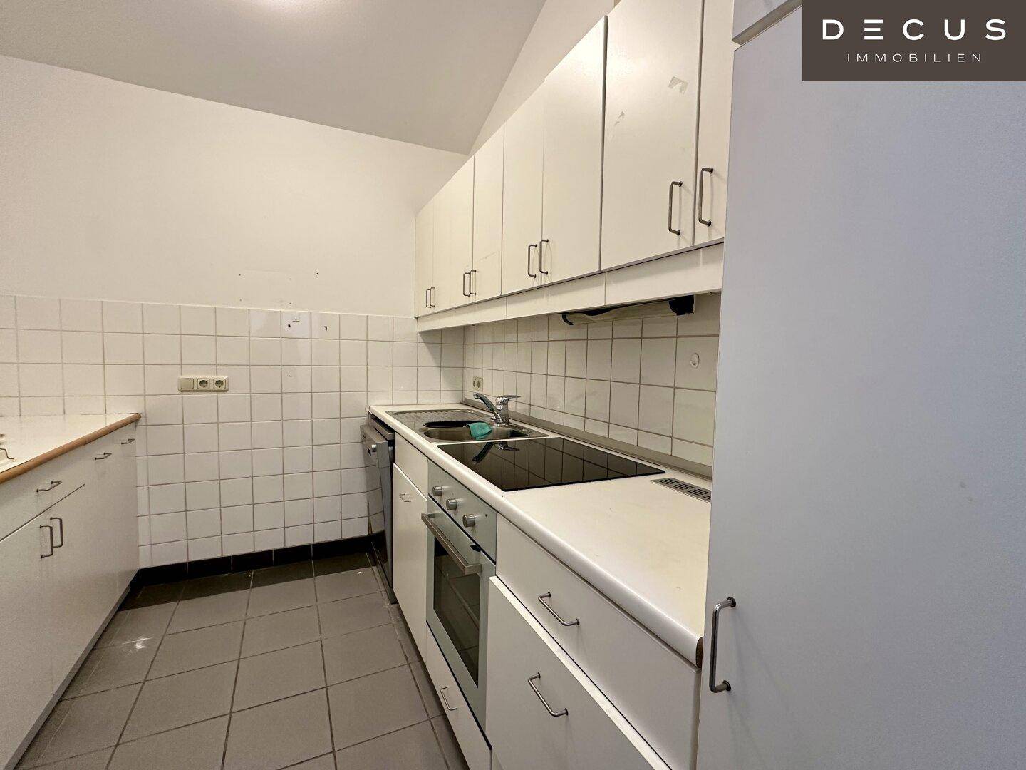 Funktionale Küche mit weißen Schränken, Fliesenboden und integrierten Geräten, in gutem Zustand.