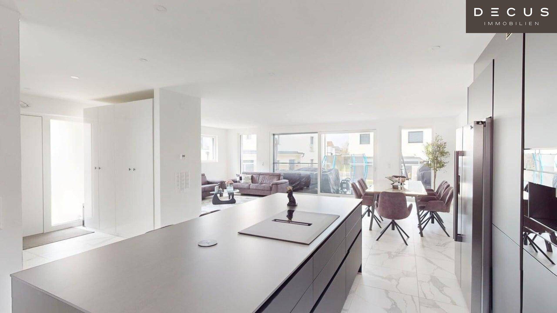 Weitläufiger offener Wohnbereich mit moderner Küche, Essbereich und Zugang zur Terrasse.
