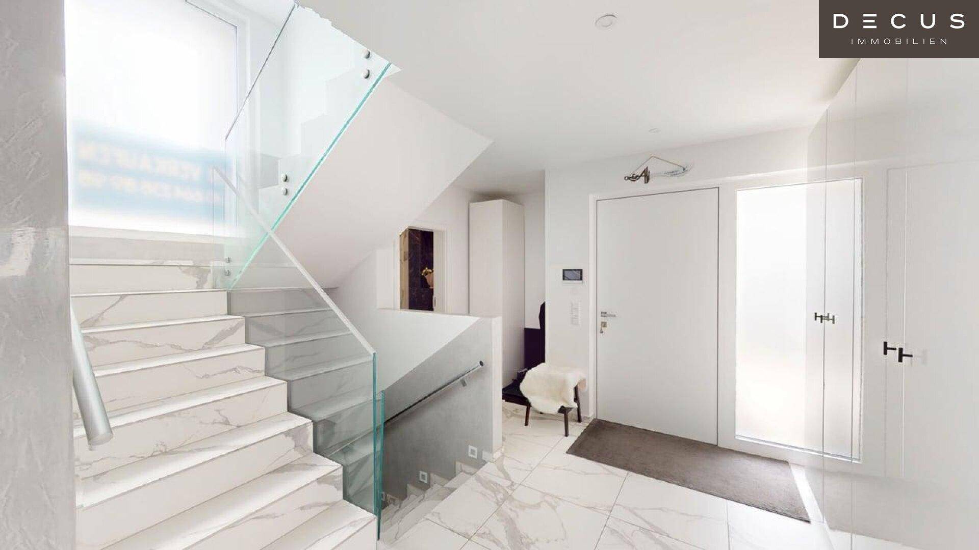 Heller Eingangsbereich mit moderner Treppe aus Glas und Marmorfliesen.