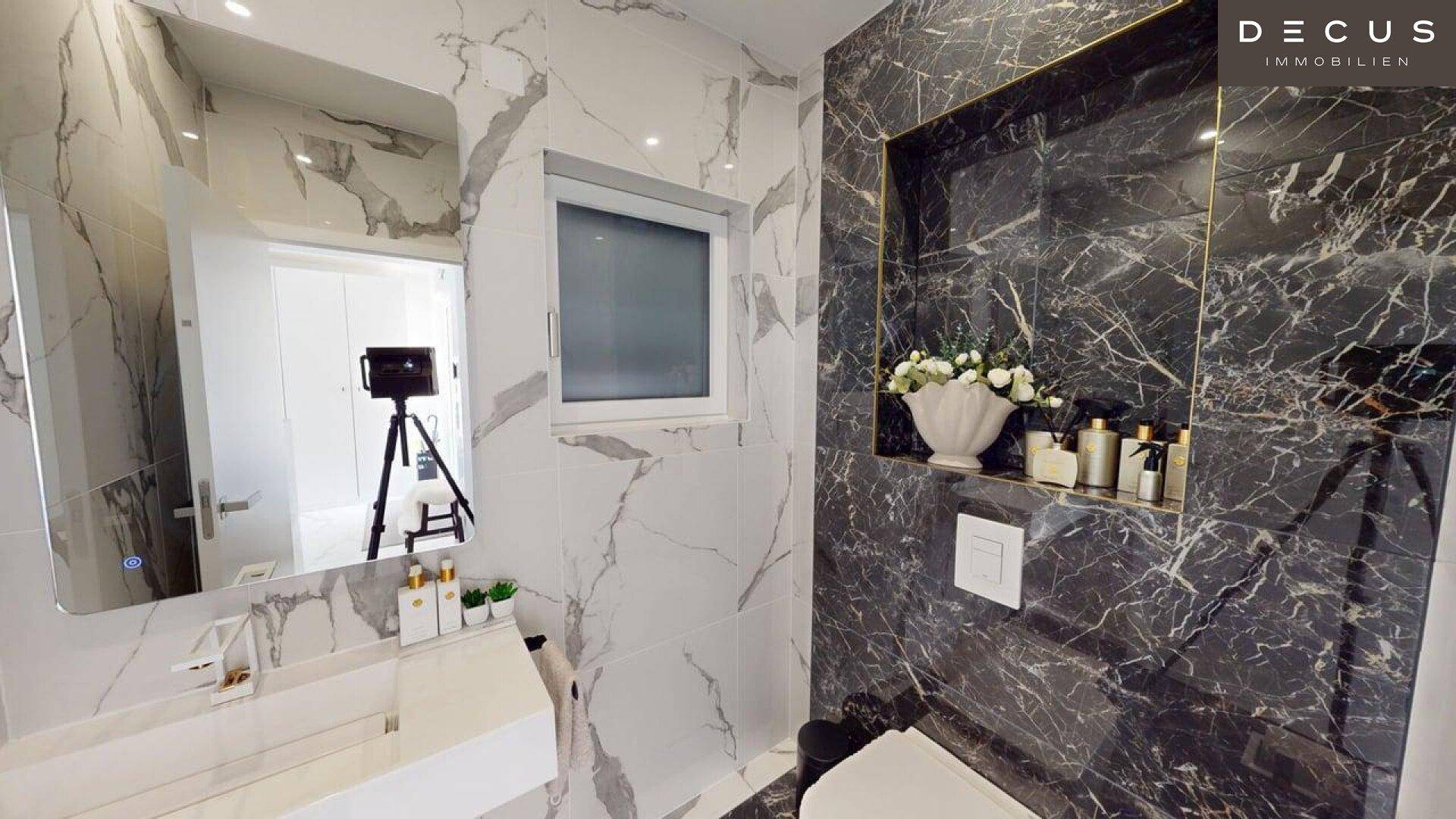 Modernes Badezimmer mit Marmorfliesen, elegantem Waschtisch und integrierter Nische.