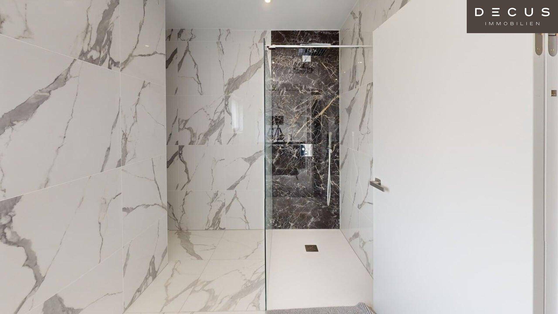 Moderne begehbare Dusche mit Glasabtrennung und eleganten Marmorfliesen.