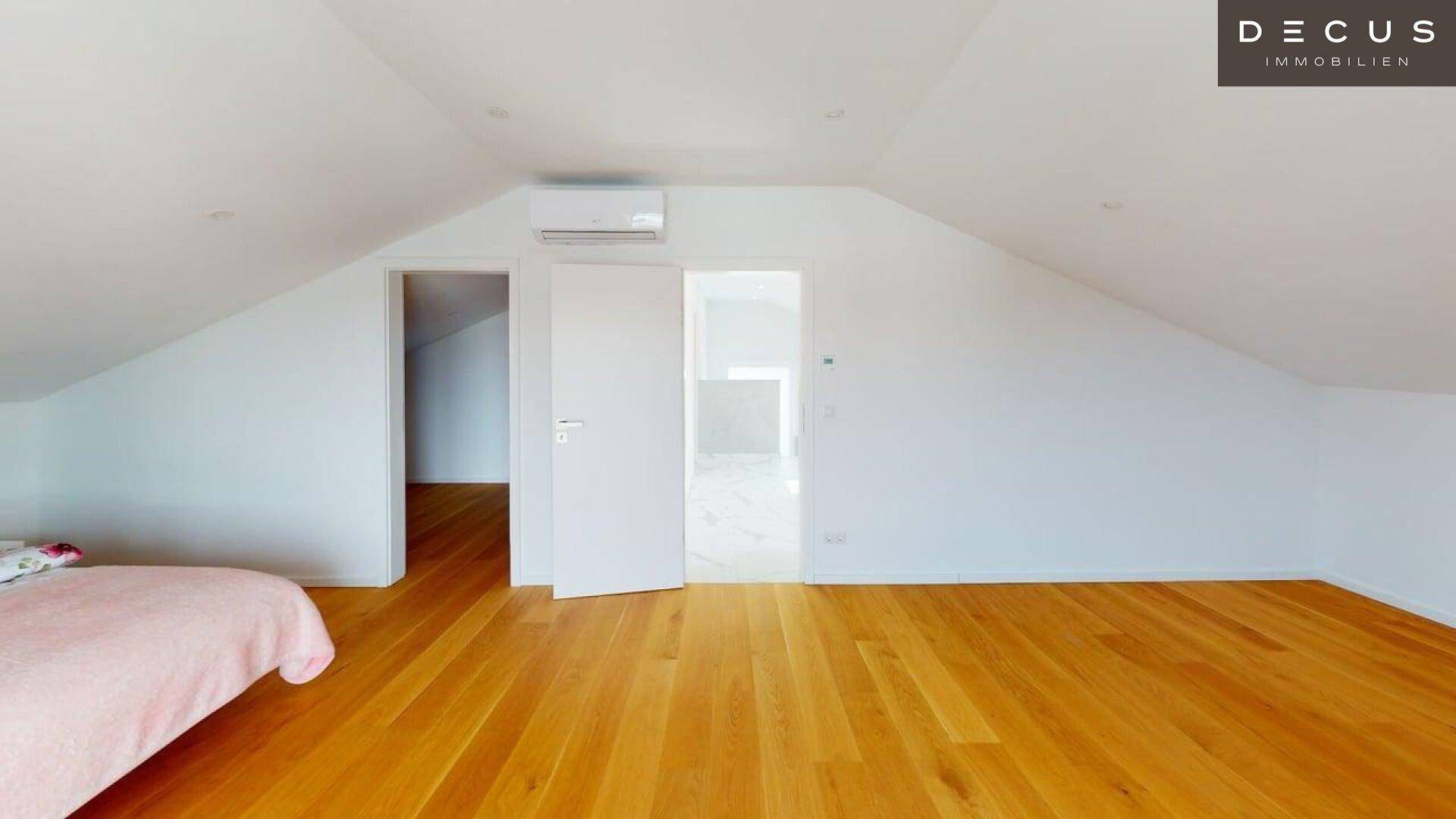 Helles Dachgeschosszimmer mit Holzboden und Zugang zu weiteren Räumen.