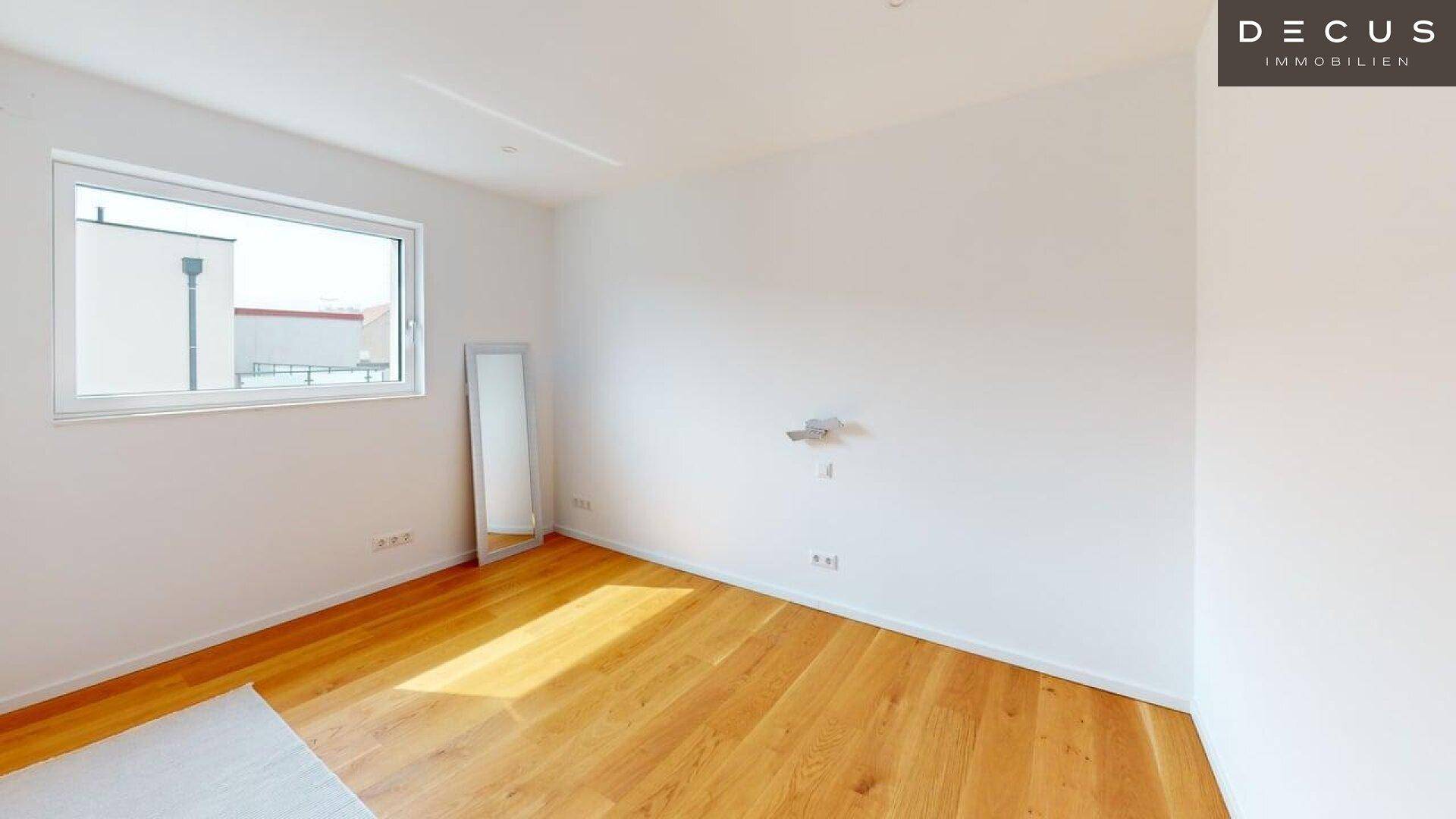 Helles, unmöbliertes Zimmer mit Holzboden und großem Fenster, ideal als Schlafzimmer.