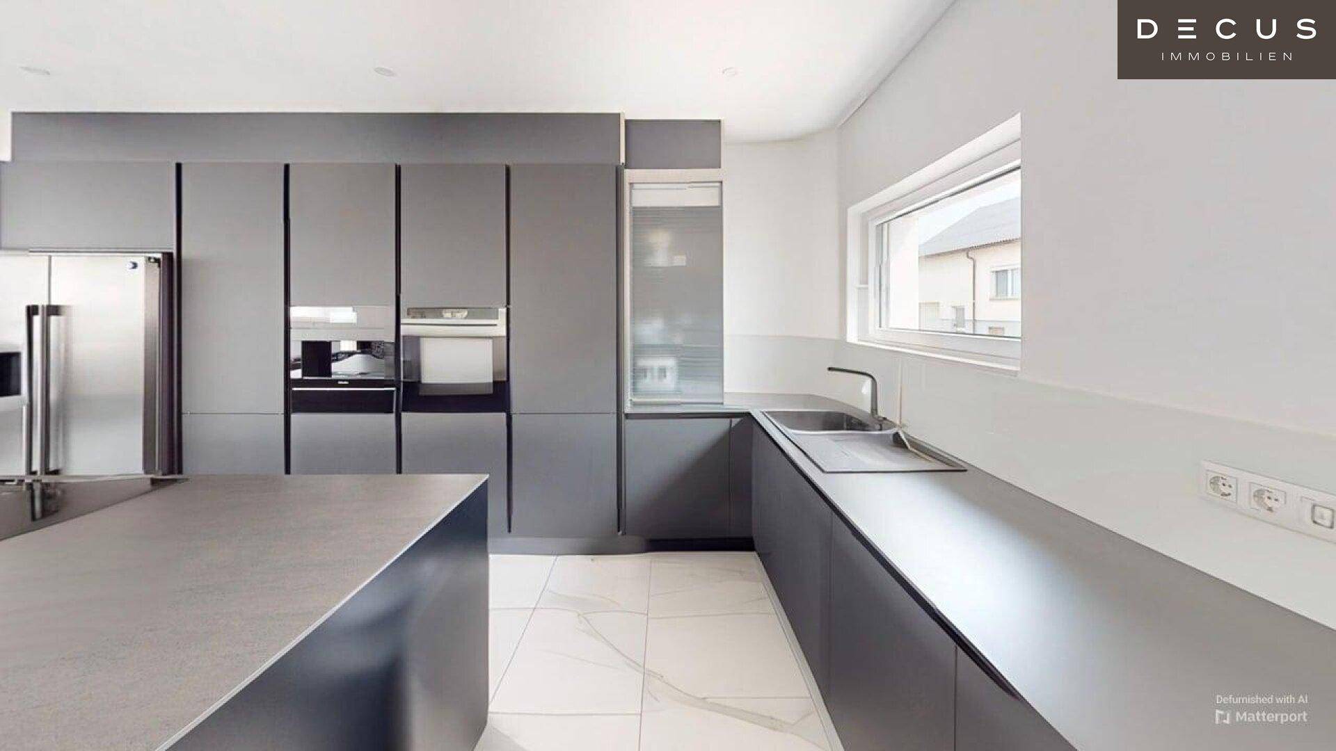 Elegante graue Küche mit minimalistischen Schränken, integrierten Geräten und Fenster.