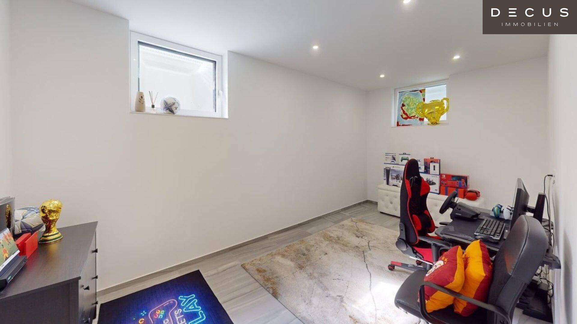 Geräumiger Hobbyraum im Keller mit Gaming-Setup und Tageslichtfenstern.