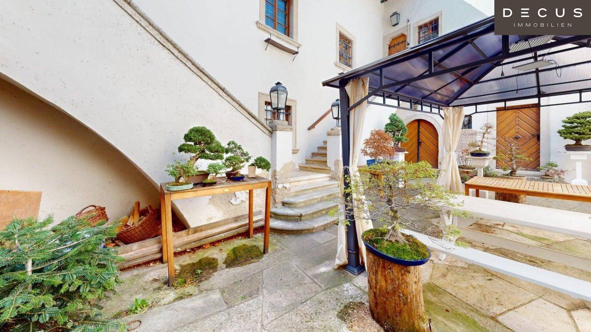 Malerischer Innenhof mit Bonsai-Bäumen, einem Pavillon und traditioneller Architektur.