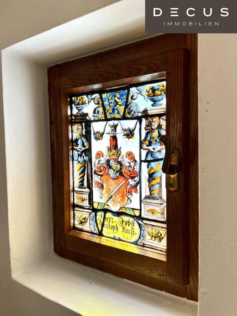 Historisches Buntglasfenster mit Wappenmotiv und traditioneller Handwerkskunst.