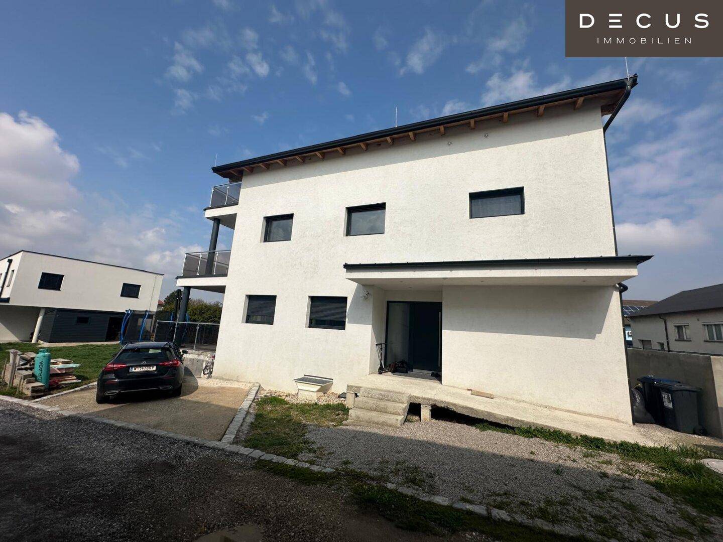 Freistehendes Einfamilienhaus mit weißer Fassade, Carport und Zufahrt.
