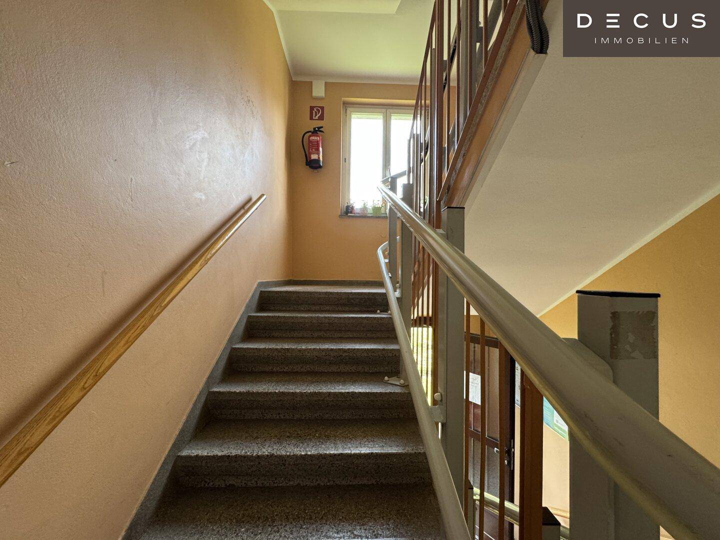 Treppenhaus mit Fenster für Tageslicht und Brandschutzvorrichtung an der Wand.