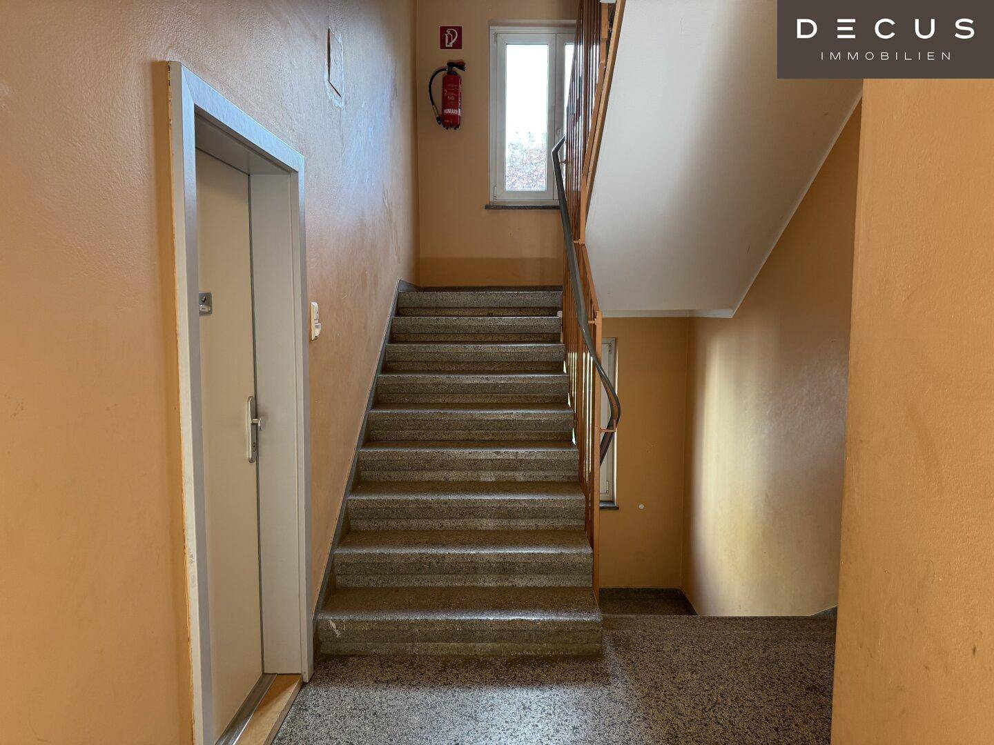 Treppenhaus mit Aufzug und Fenster, bietet Zugang zu den verschiedenen Stockwerken.
