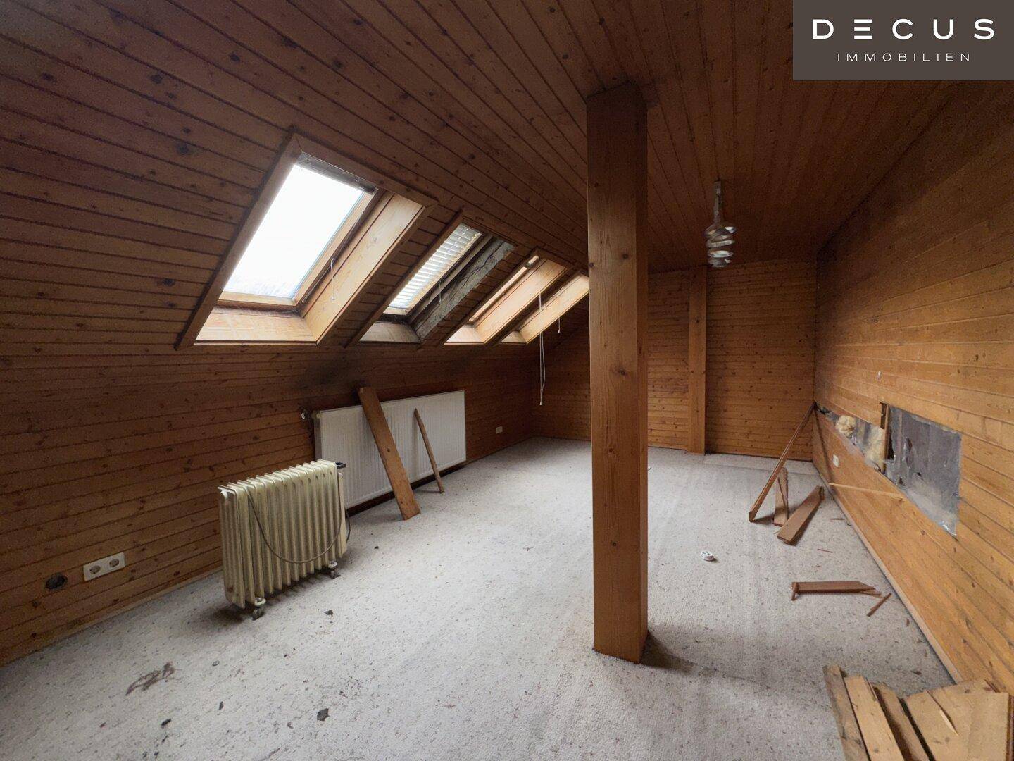 Ausgebauter Dachbodenraum mit Holzverkleidung, Dachfenstern und Heizkörpern.