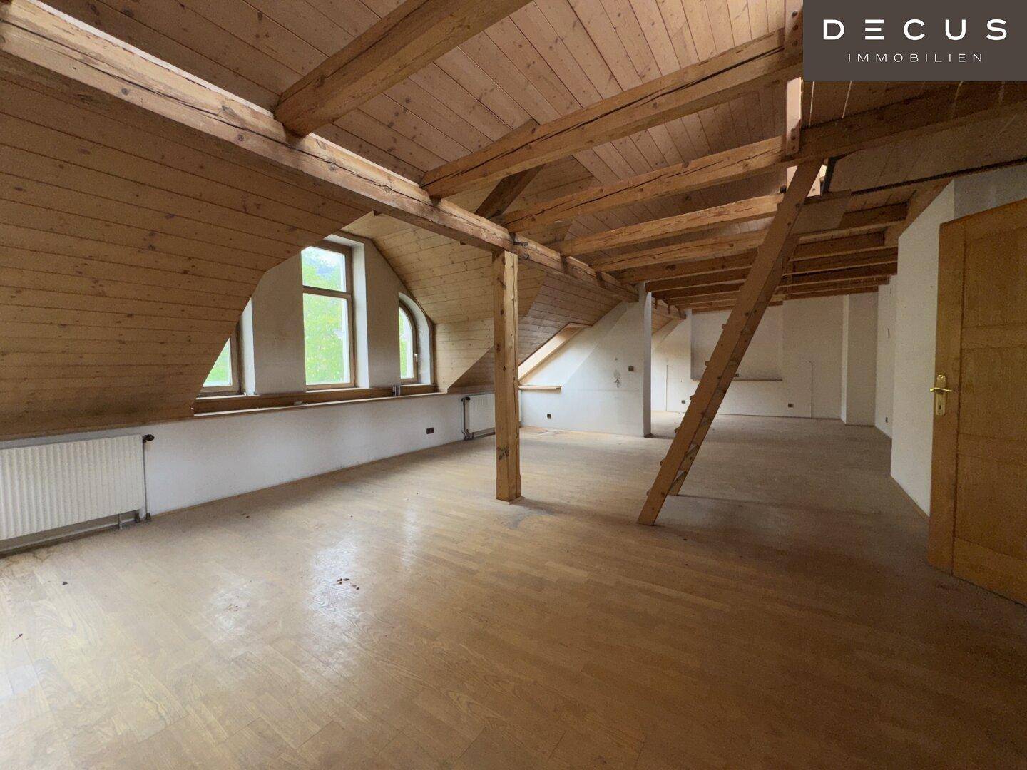 Geräumiger Dachbodenraum mit sichtbaren Holzbalken, Holzboden und Dachschrägen.
