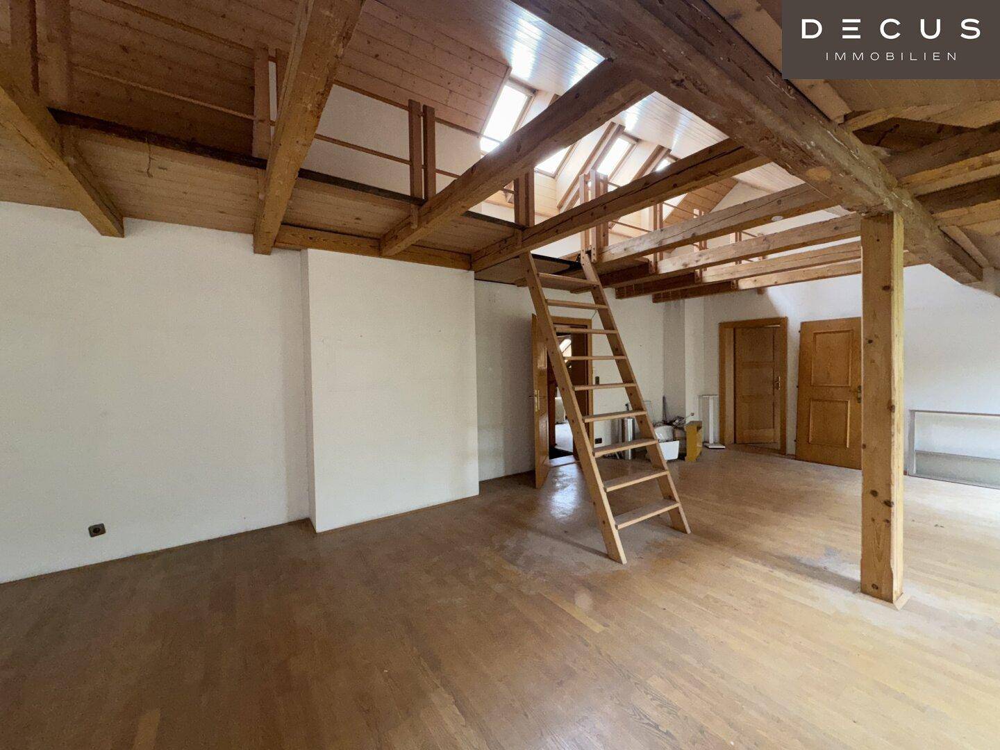 Dachbodenraum mit Holzbalken, Dachfenstern und einer Leiter zu einer oberen Ebene.